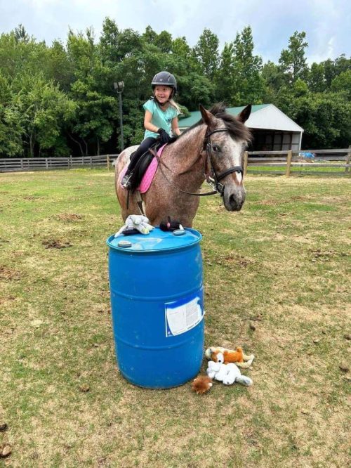 kid riding a horse around a barrel - redbird equestrian