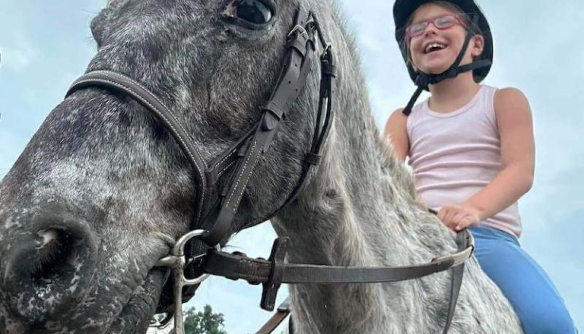 child having fun riding a horse smiling - redbird equestrian