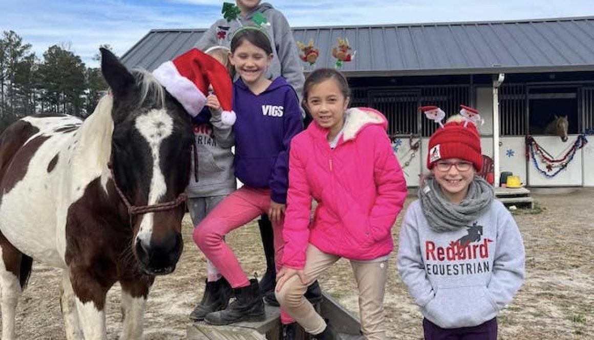Kids with a horse in Santa hats at Redbird Equestrian