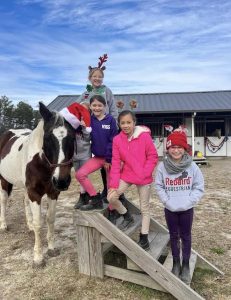 Kids with a horse in Santa hats at Redbird Equestrian