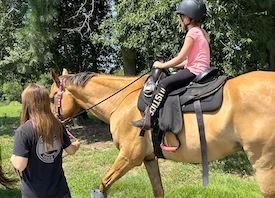 child riding a horse at Redbird Equestrian pony camp